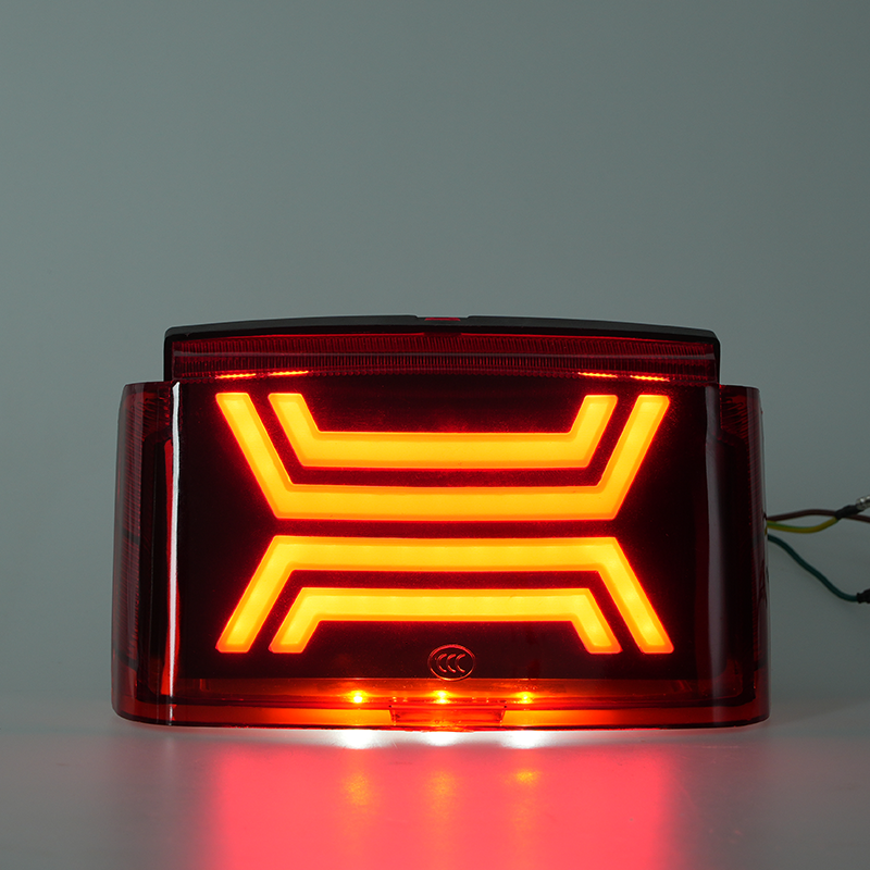 Illuminated motorcycle LED tail brake light, bright orange‑red geometric flowing light effect